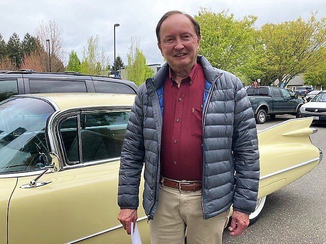 Dick Pust posing with a yellow 1960s caddy. This vehicle is an echo of his former 1957 Chevrolet Bel Air convertible of the same hue, which Dick purchased in 1960 for $1,795. It was a car that he dearly loved.